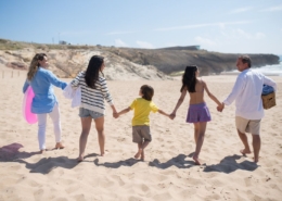 Familia caminando de la mano por la playa durante las vacaciones de verano