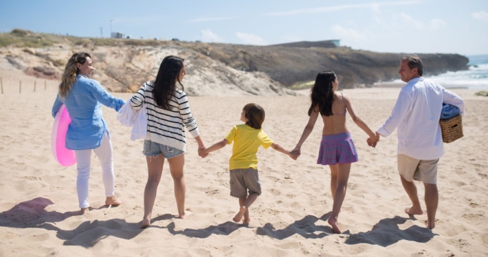 Familia caminando de la mano por la playa durante las vacaciones de verano